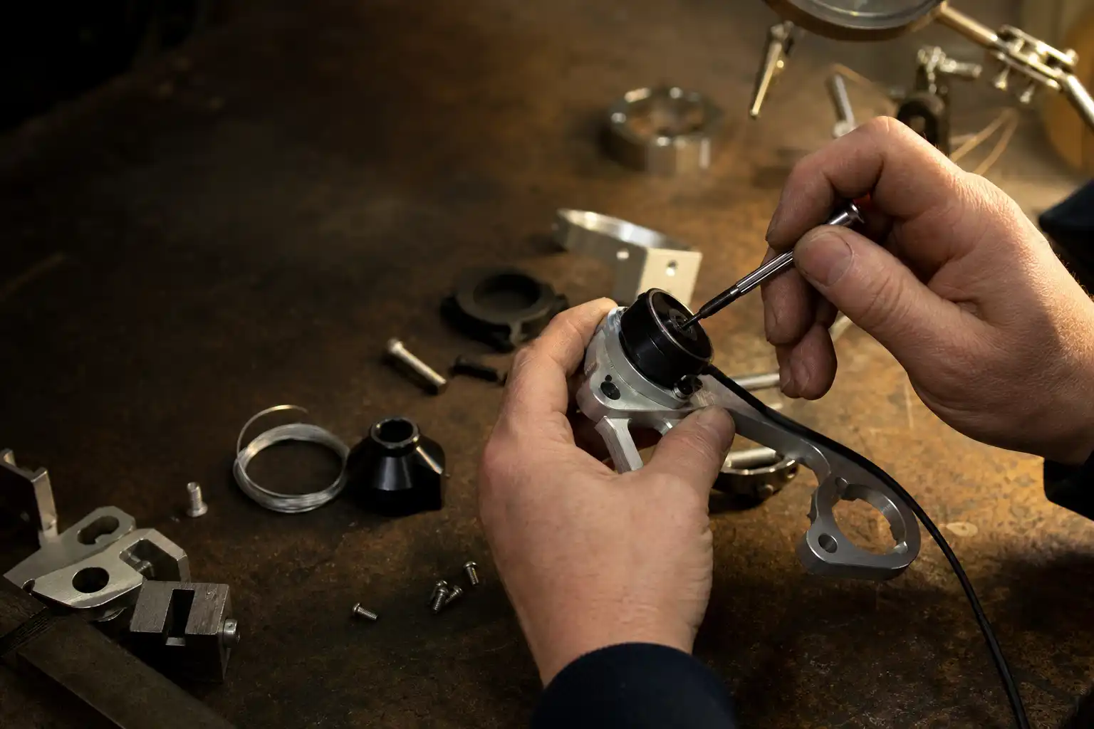 Hands fitting a sensor housing to a machined bracket at a workshop bench