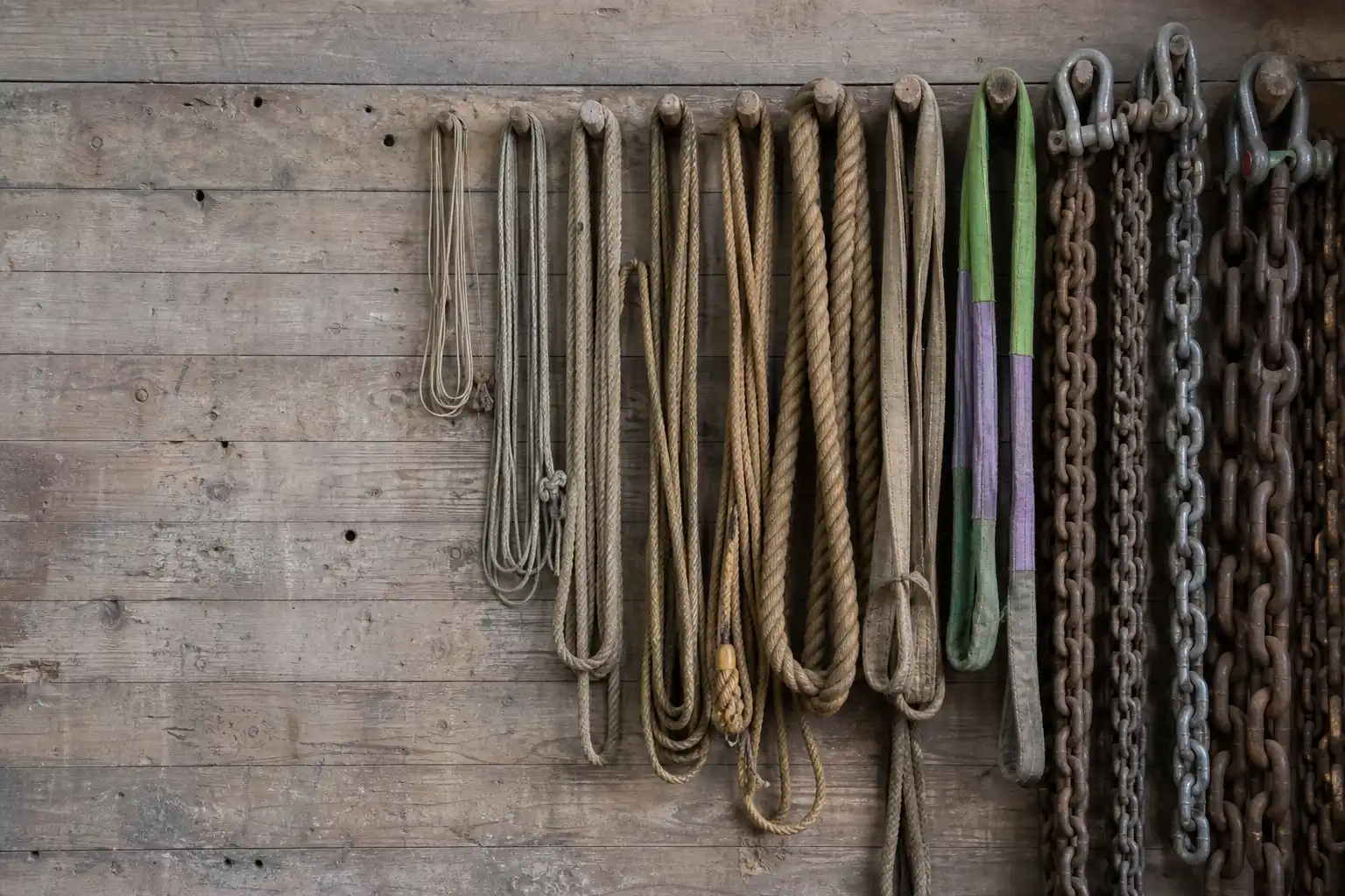 Ropes, slings and chains hung on a rigging loft wall in ascending thickness