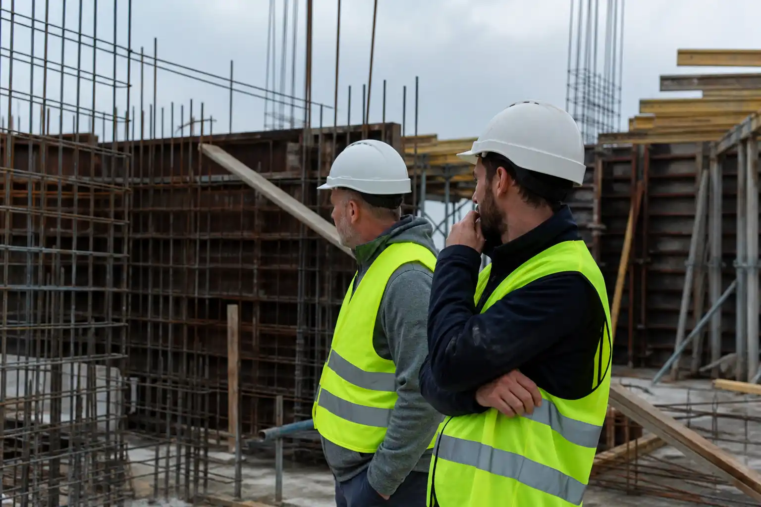Two engineers in high-visibility vests reviewing work on a site